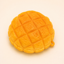NOLLUMI Golden Bun Squishy with a warm orange-gold crosshatch top and small hanging loop
