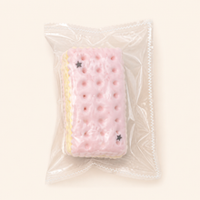 NOLLUMI Macaron Sandwich Cookie Squishy in its clear sealed wrapper, with pink biscuit layers, cream filling and star details