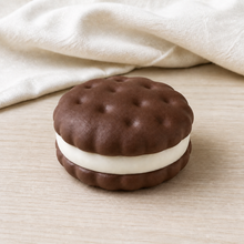 Real product photo of the NOLLUMI Sandwich Cookie Squishy in Coffee on ivory linen and light wood