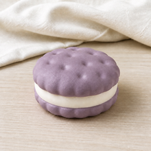 Real product photo of the NOLLUMI Sandwich Cookie Squishy in Taro Purple on ivory linen and light wood