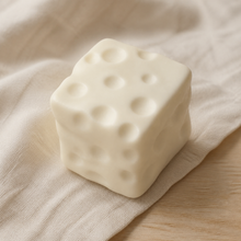 Real product photo of the NOLLUMI Tiny Cheese Squishy on a warm neutral setting